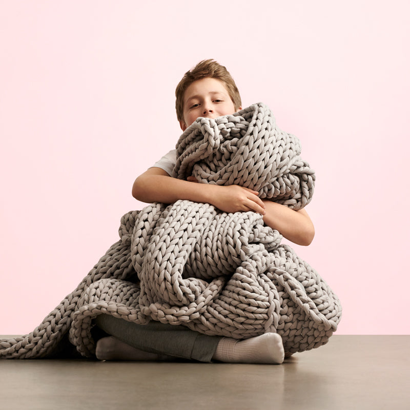 a boy cuddle up with bearaby's child weighted blanket